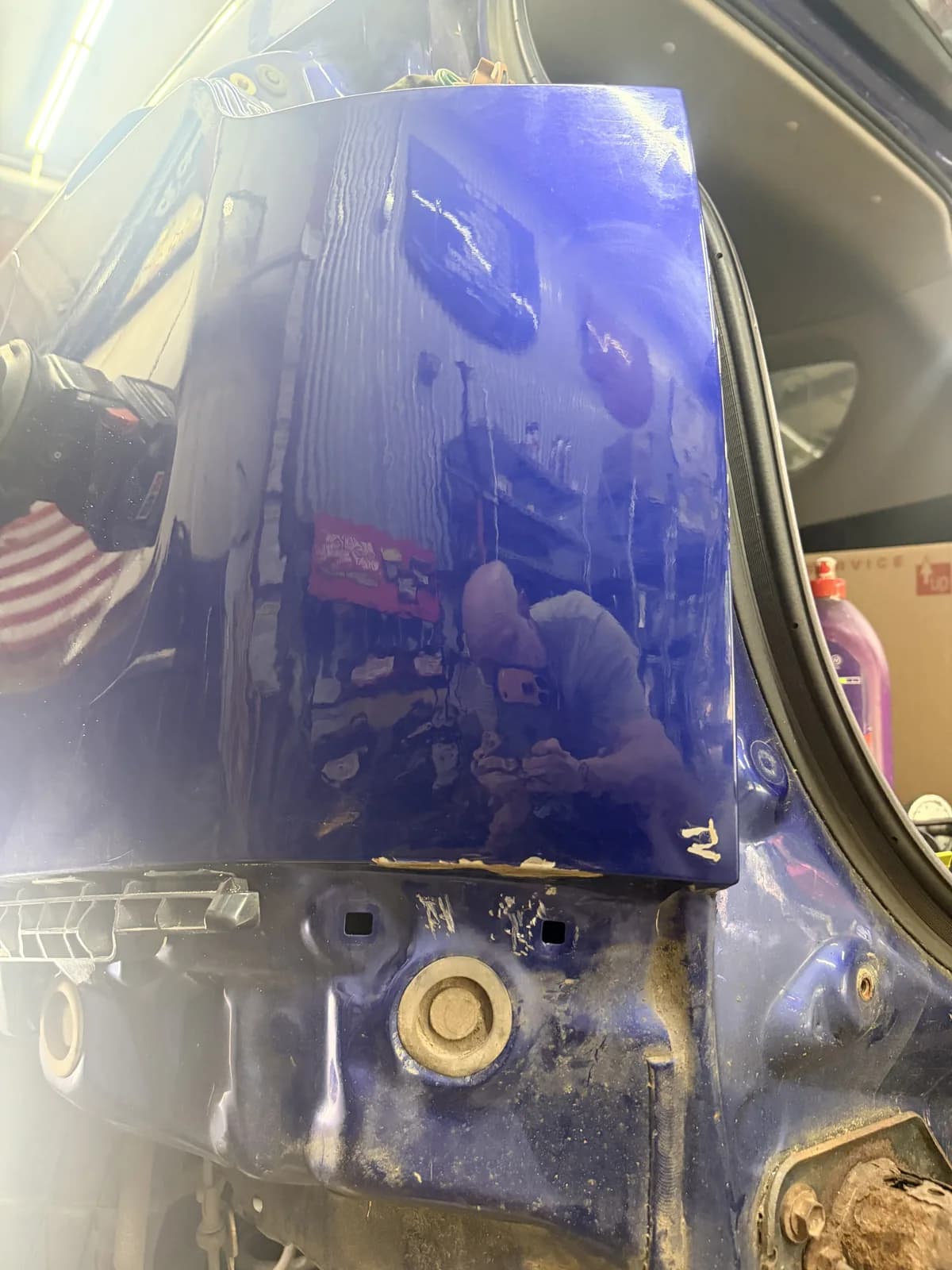 The same blue quarter panel after repair, reflection running unbroken.
