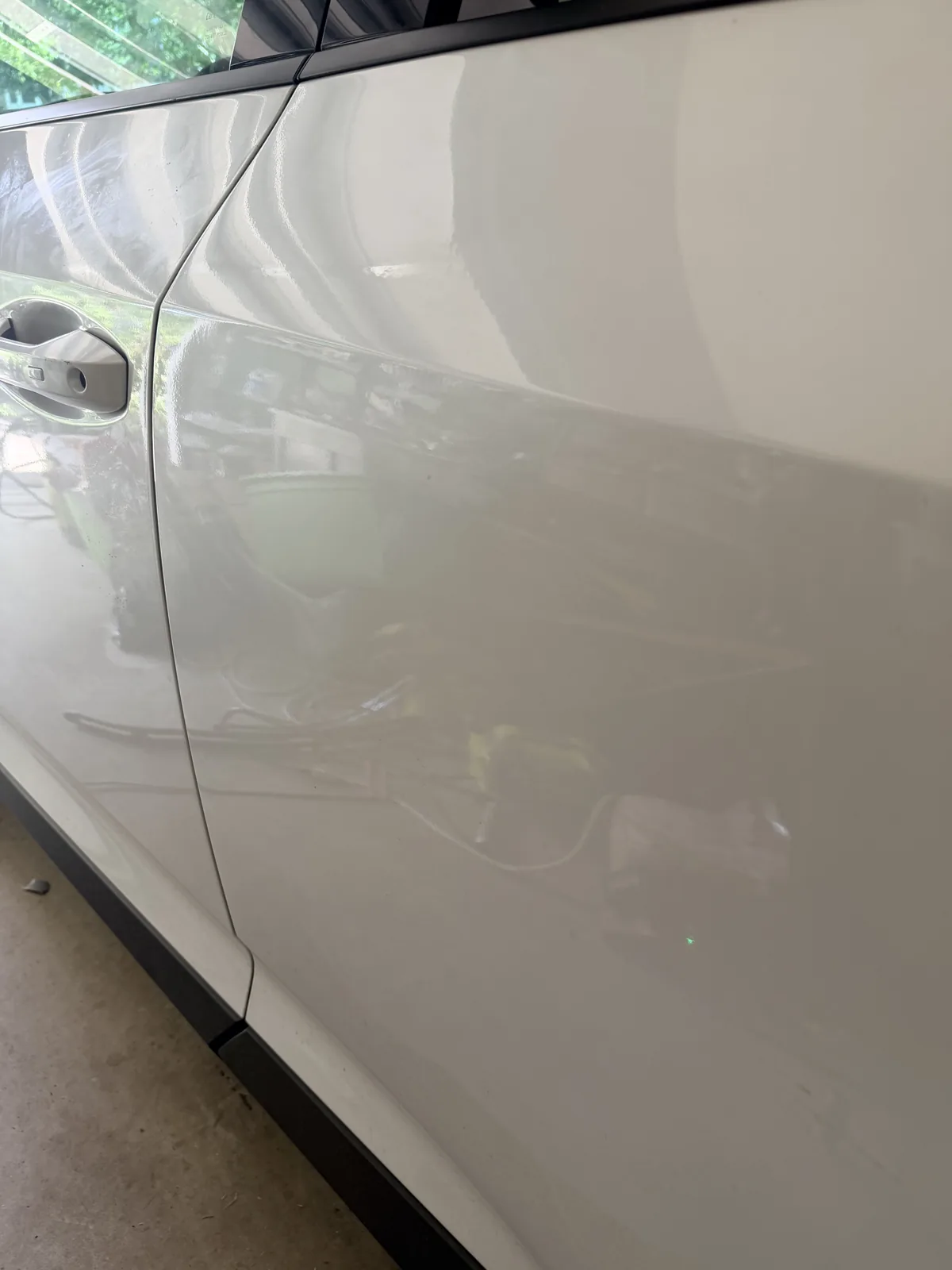 The same white SUV door after repair, the crease gone.