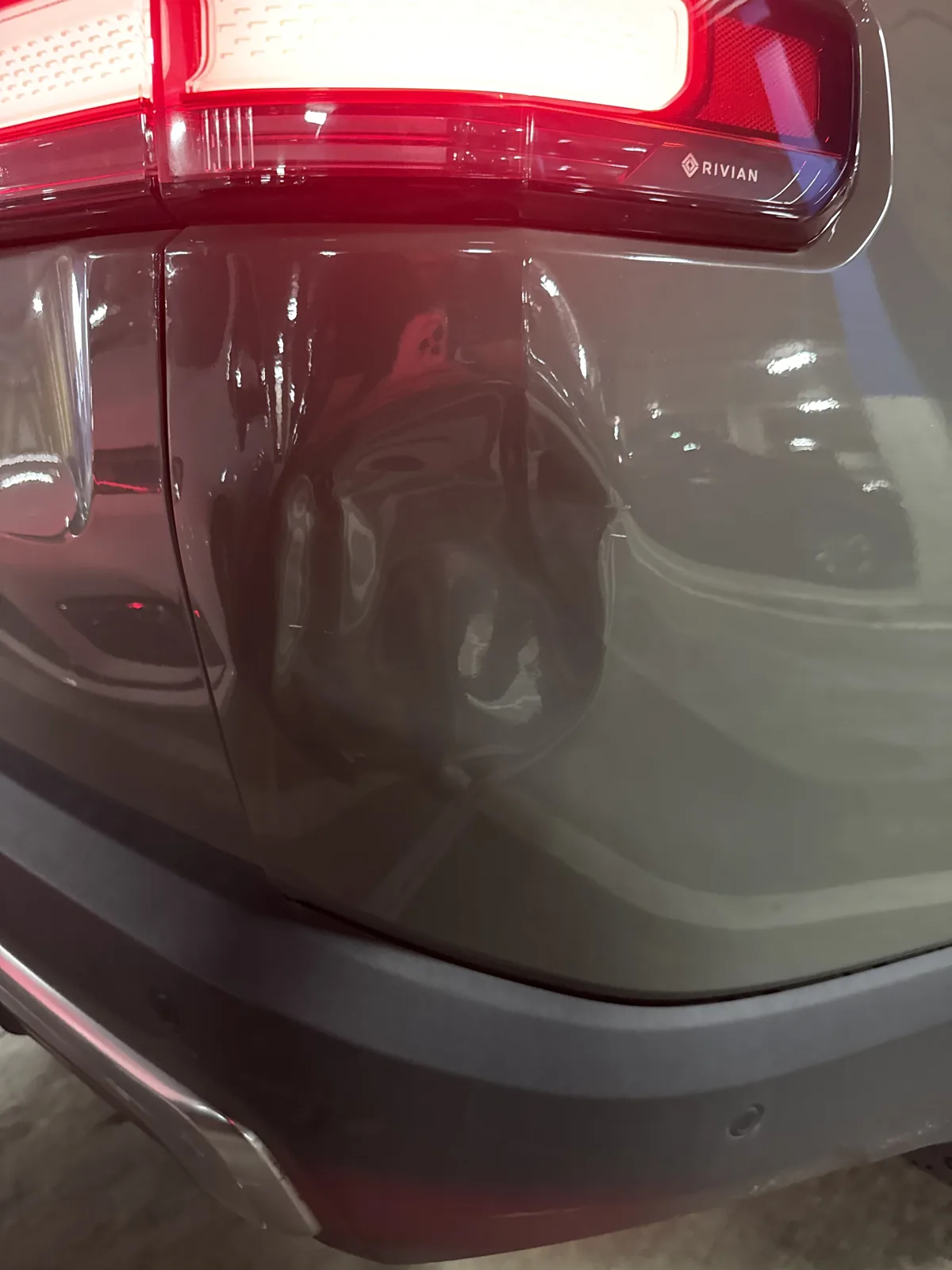 Close view of the R1S quarter panel dent beside the taillight, paint intact.