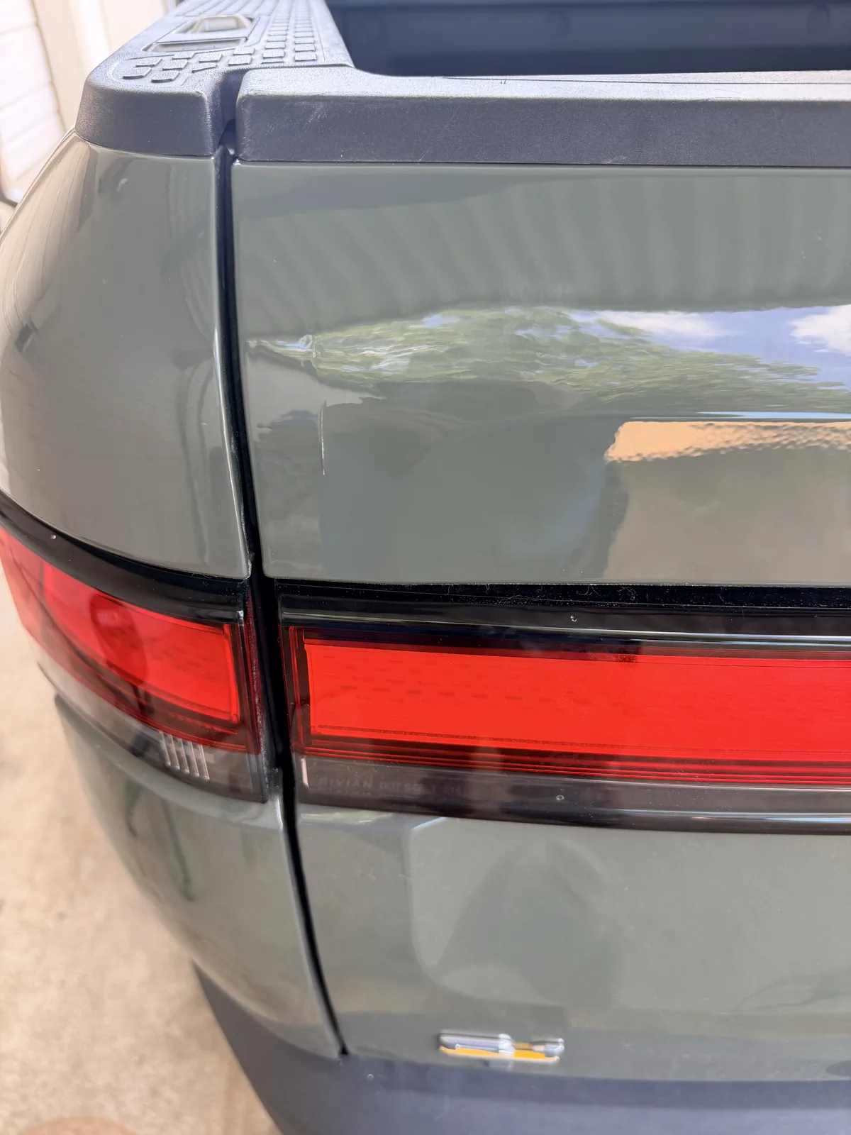 Close detail of the repaired R1T tailgate beside the taillight bar, with no trace of the dent.